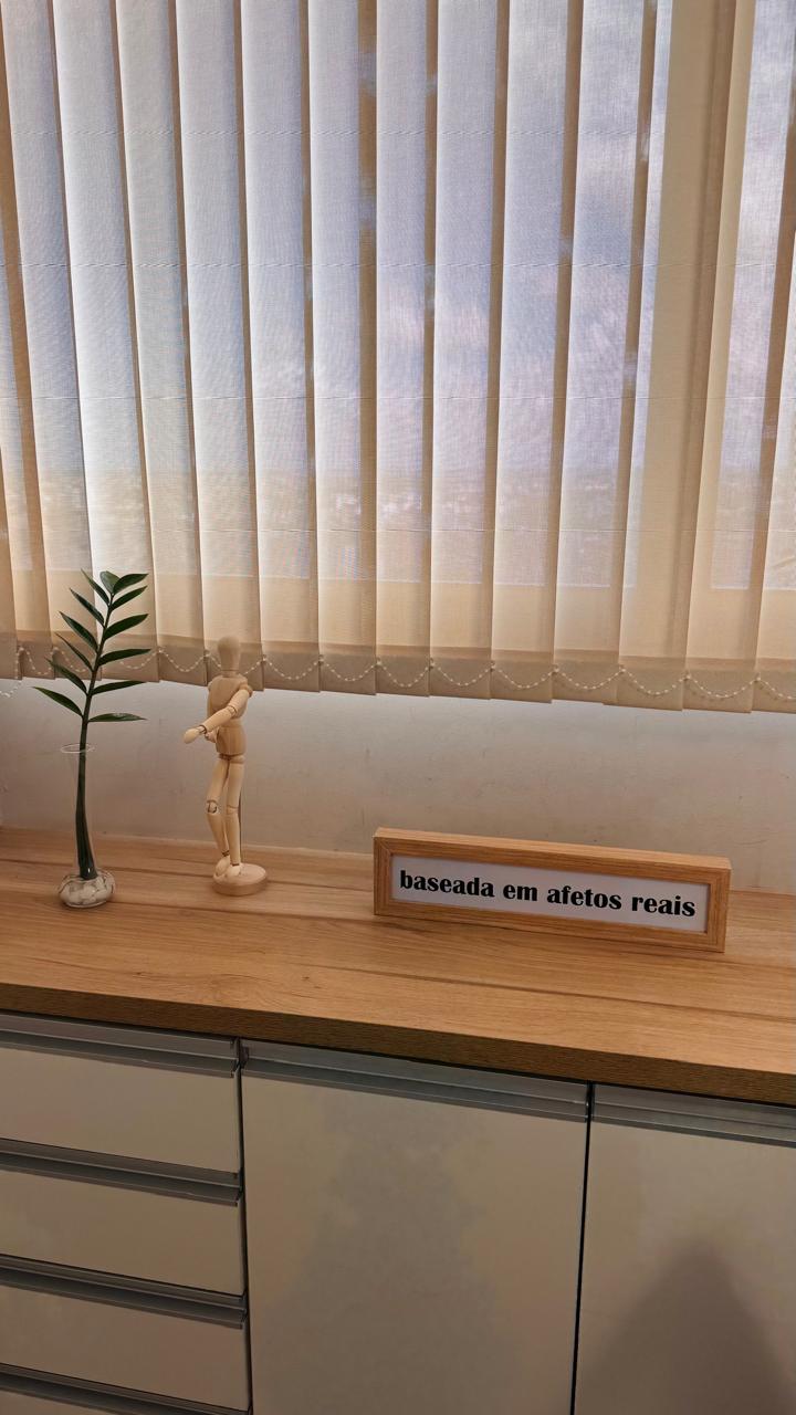 Bancada com planta, figura de madeira e quadro baseada em afetos reais.