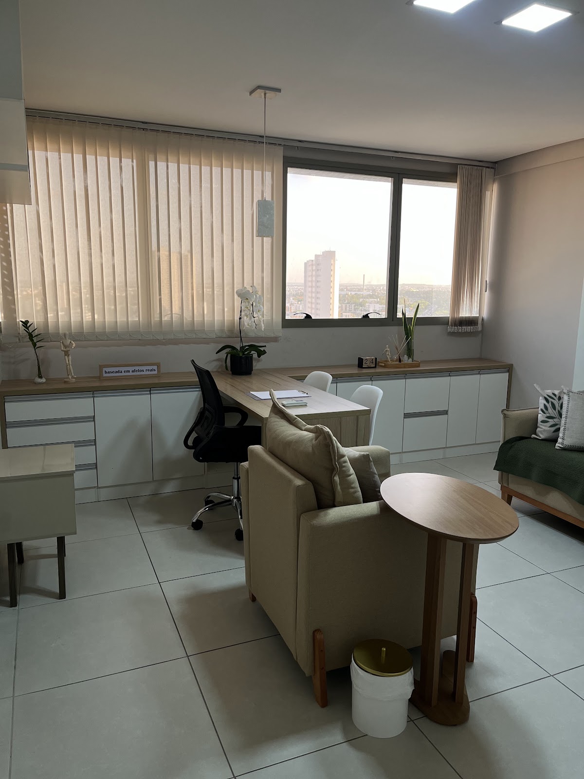 Consultório Harmoniê visto das poltronas, com bancada, janela e mesa de atendimento
